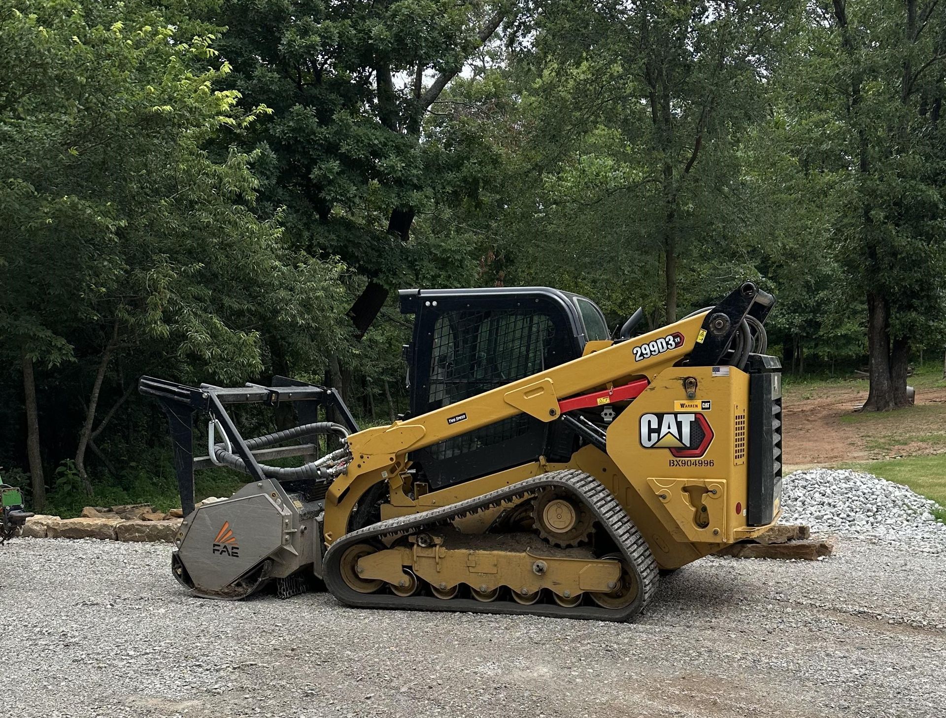 A yellow cat skid steer is parked on a gravel road.