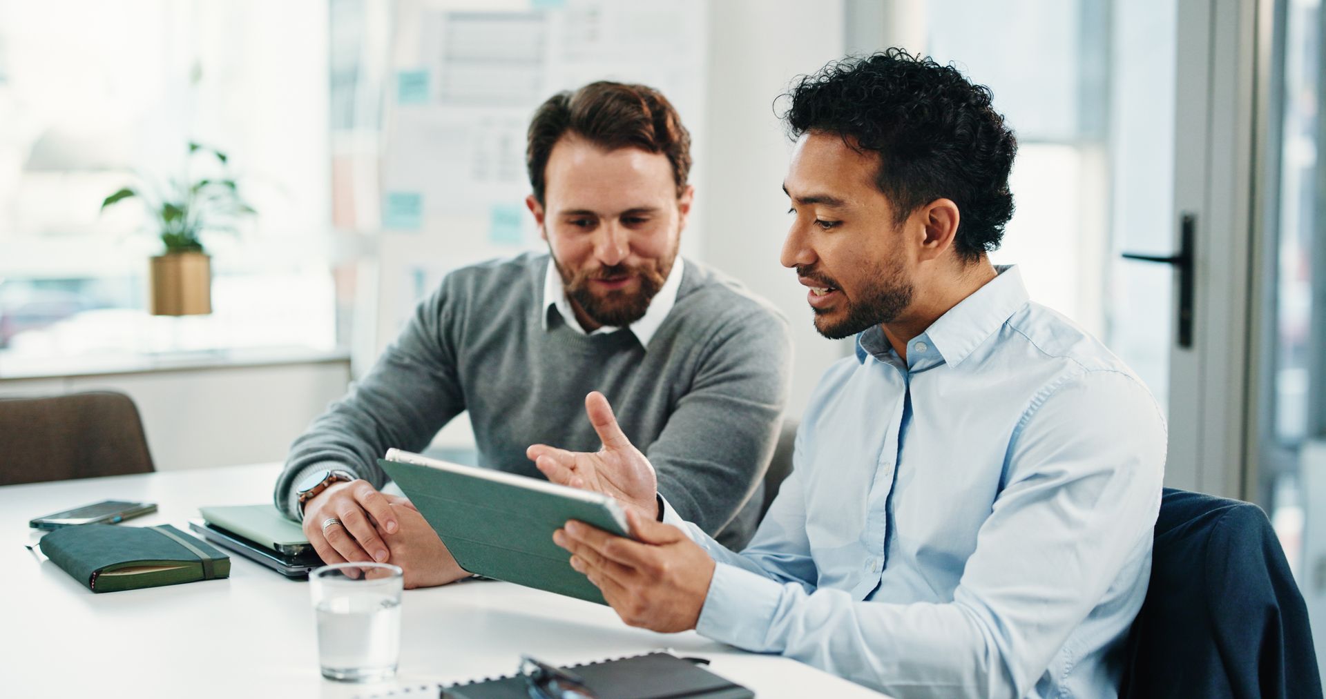 Two coworkers reviewing a tablet at a desk in a bright office