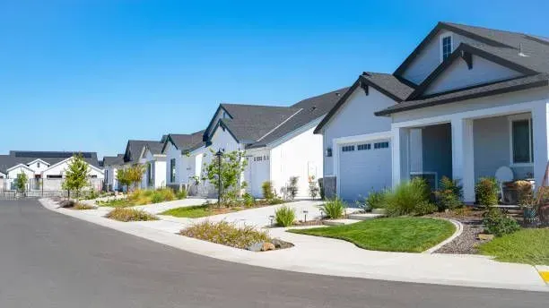 Suburban street with row of modern white houses and garages on a sunny day