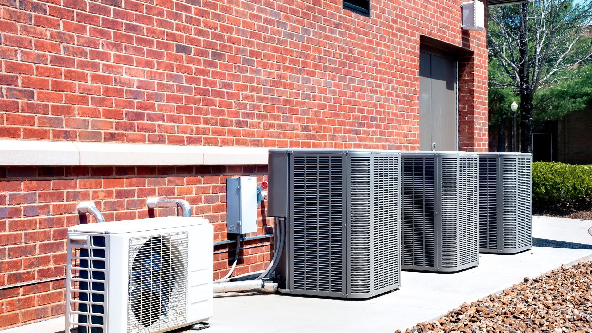Air conditioning units lined up against a brick building.