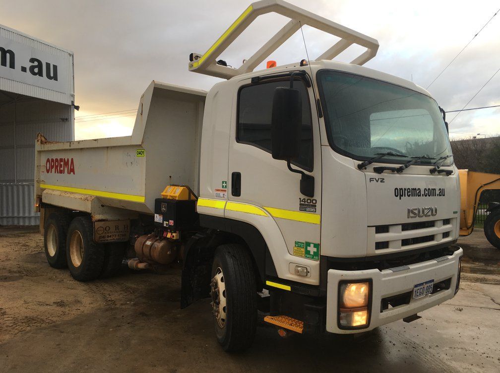 A white dump truck is parked in front of a building.