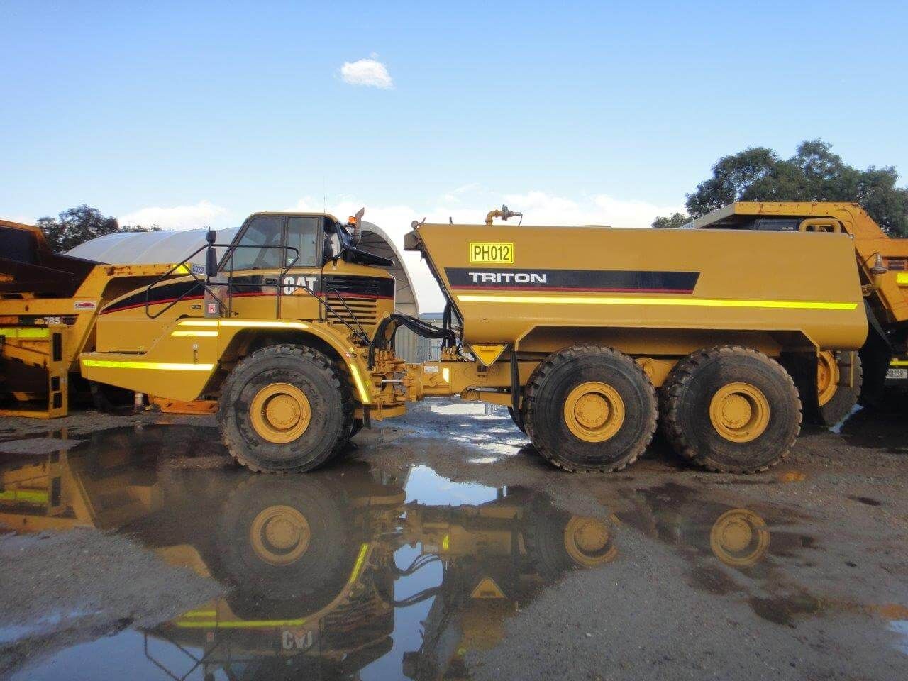 A yellow dump truck with a tank on the back is parked in a parking lot.