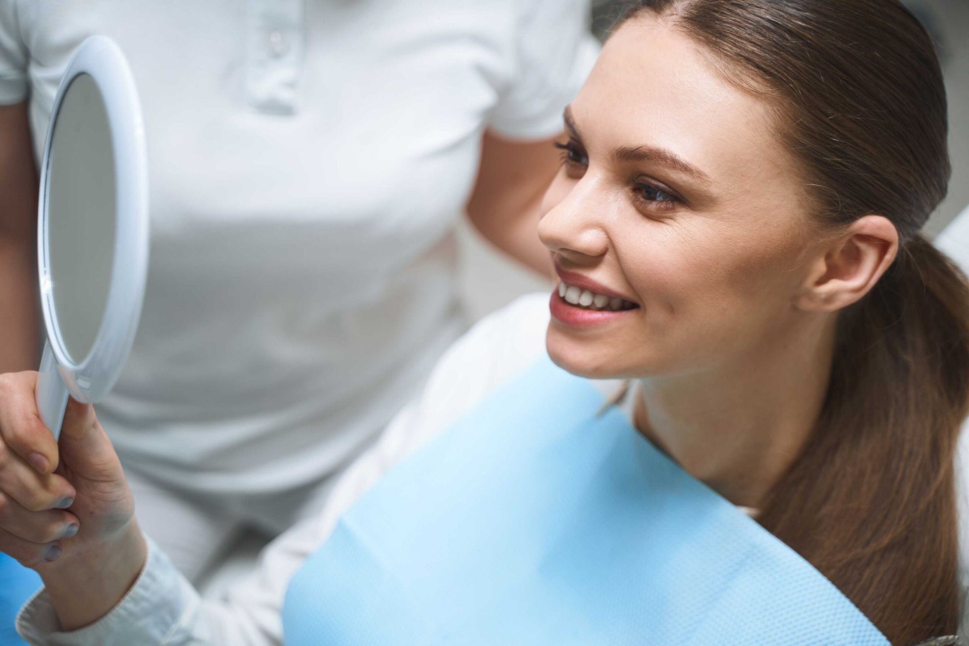 Patient looking at her smile in a mirror.