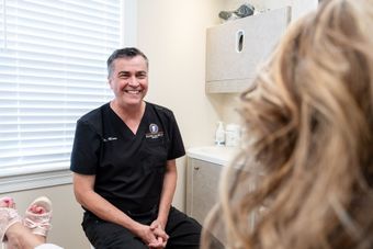 Dr. Russell Mann sitting down with a patient in a window-lit treatment room at Mann Family Dental in Manchester, NH