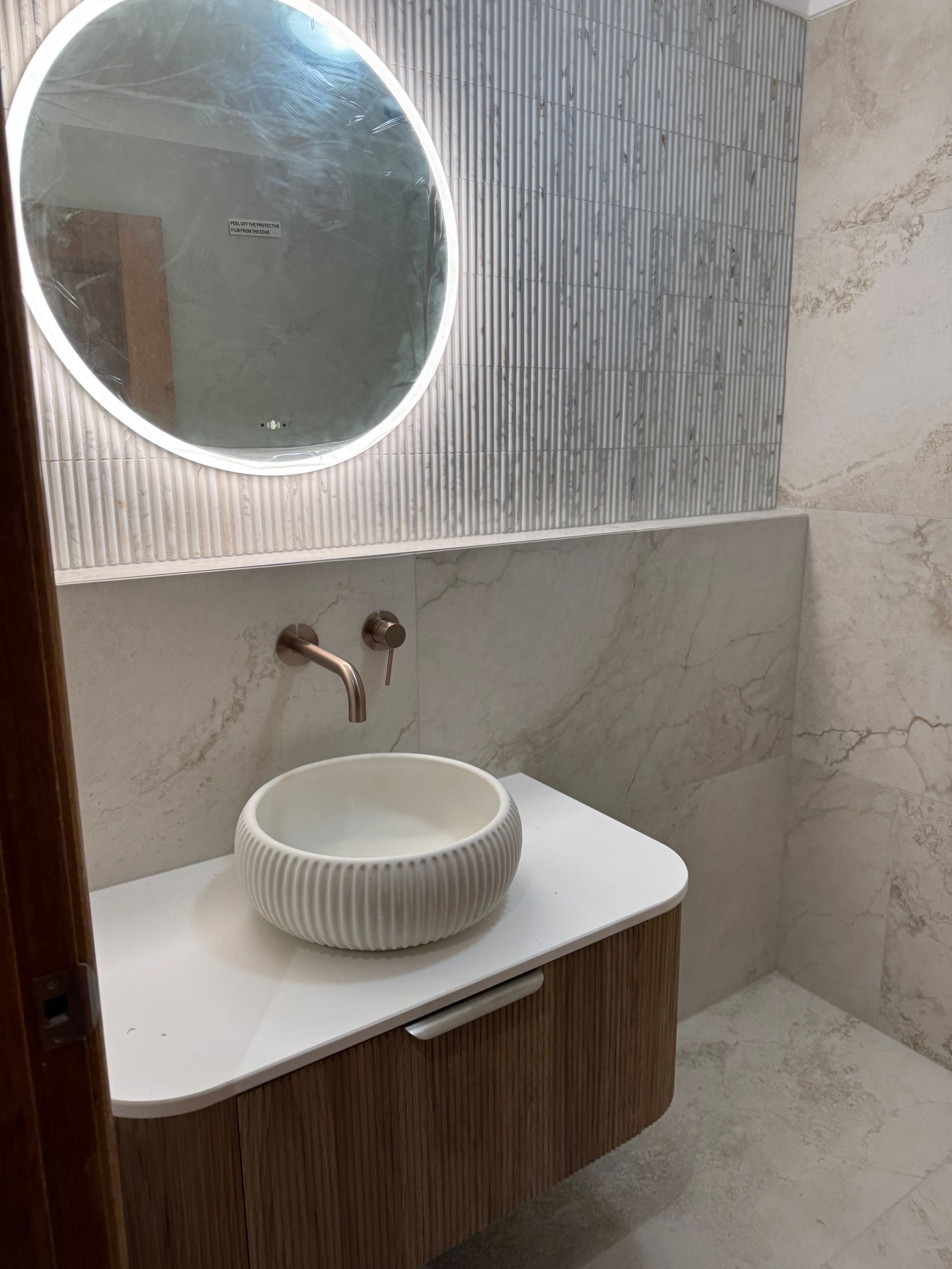 Modern bathroom with a round mirror, vessel sink, and textured walls  — Fair Plumbing In Kembla Grange, NSW