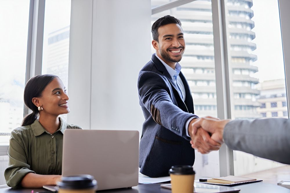 A Man And A Woman Are Shaking Hands In An Office — Successful Resumes in Wonga Beach, QLD