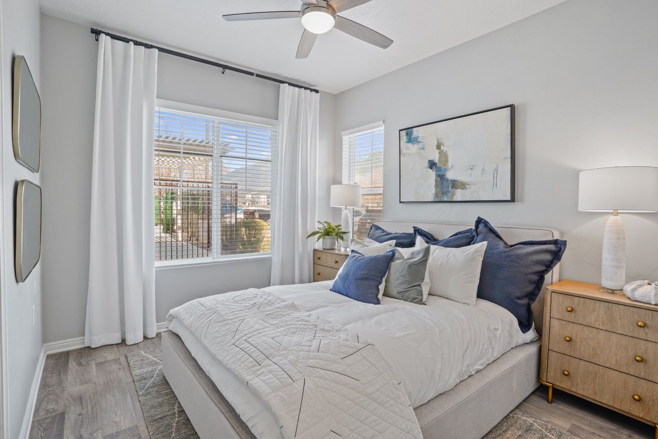 Bright bedroom with a large bed, white curtains, two wooden nightstands, and abstract wall art at Viewpointe—offering Pleasant Grove apartments.