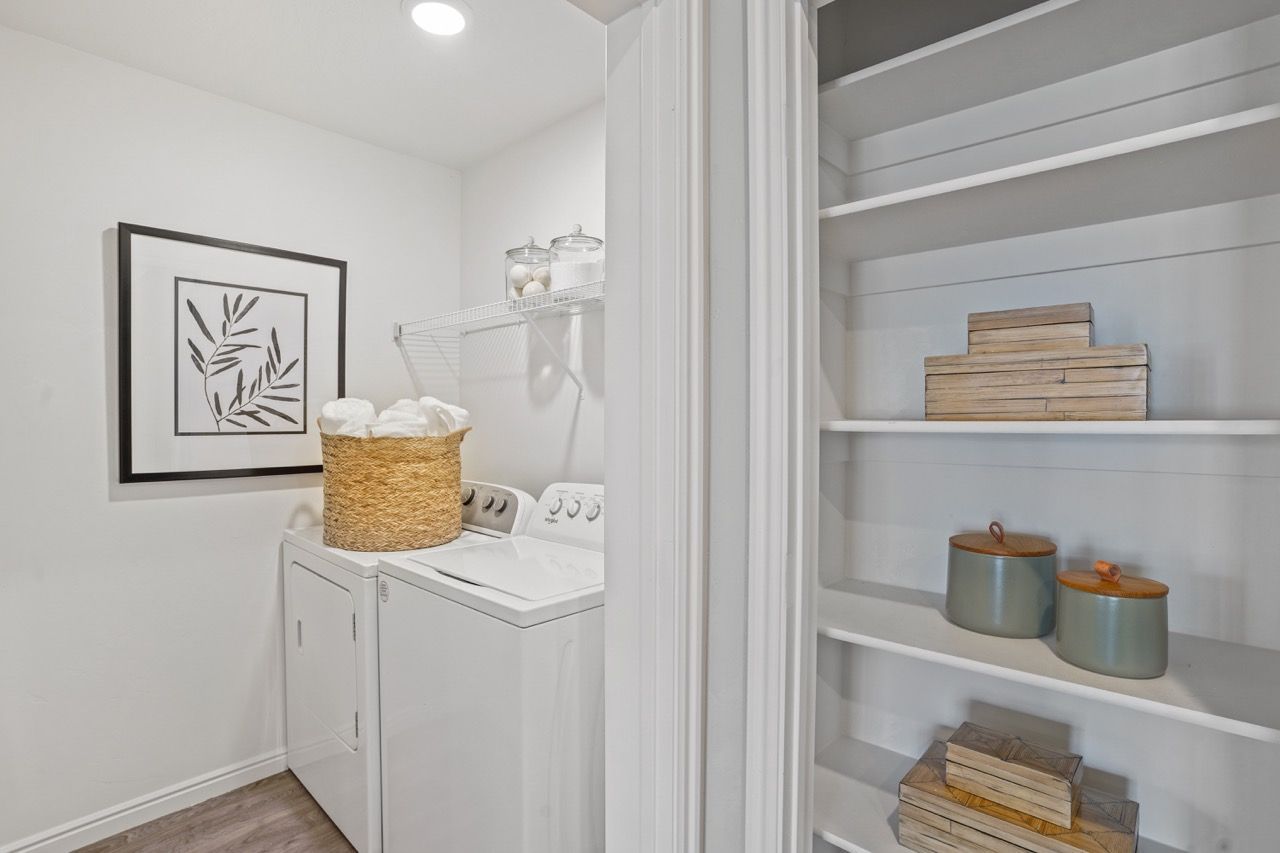 Laundry room with a washer and dryer, shelving, and woven storage baskets at Viewpointe—offering Pleasant Grove apartments for rent.