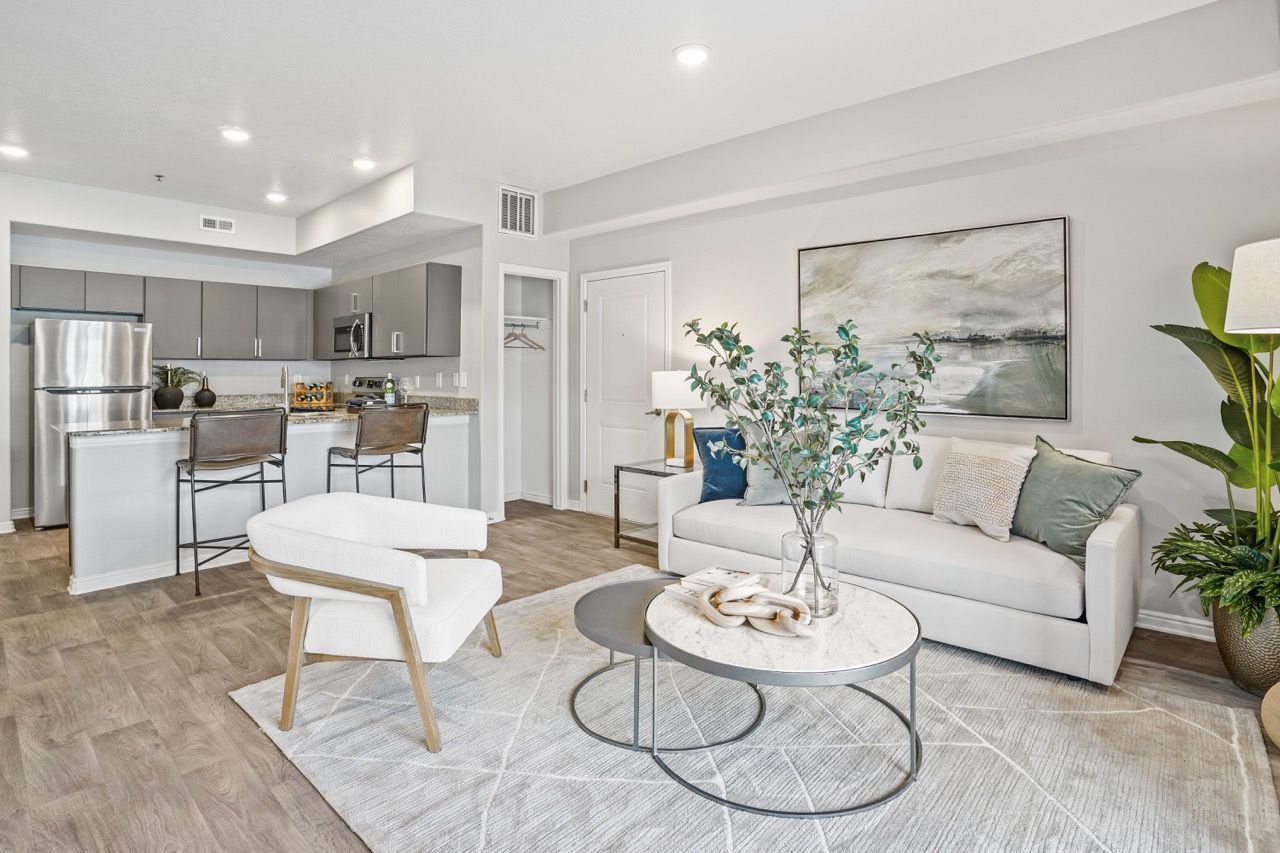 Open-concept living room with white sofa, chair, coffee table, and a modern kitchen in the background at Viewpointe—offering pet-friendly apartments in Pleasant Grove, UT.
