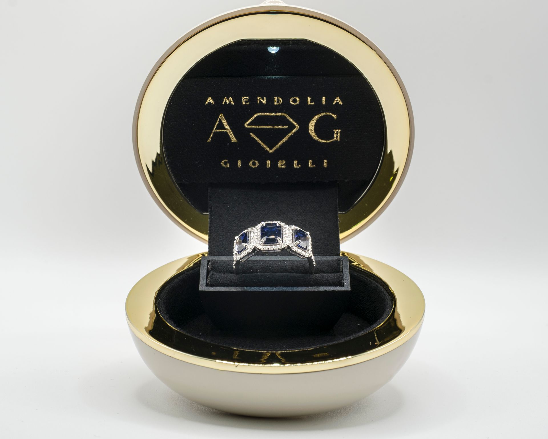 Anello in un portagioie d'oro aperto, su un espositore di velluto nero.
