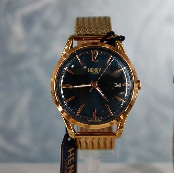 Orologio color oro con quadrante blu navy e cinturino in maglia, il marchio è