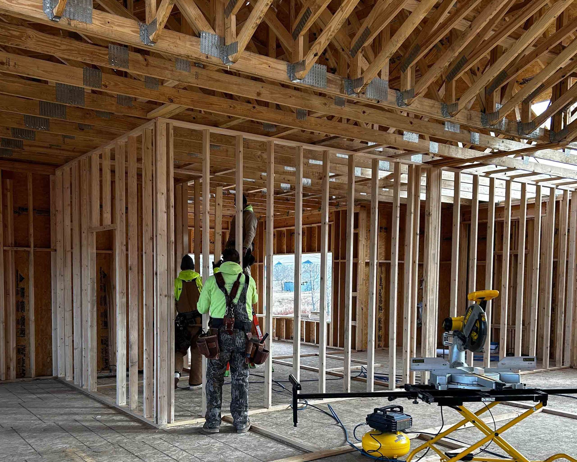 A group of construction workers are standing inside of a building under construction.