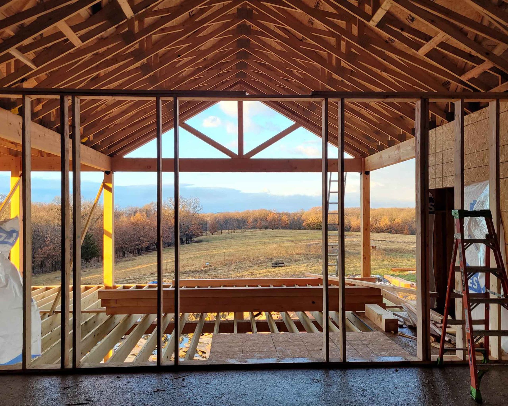 The inside of a building under construction with a view of a field.