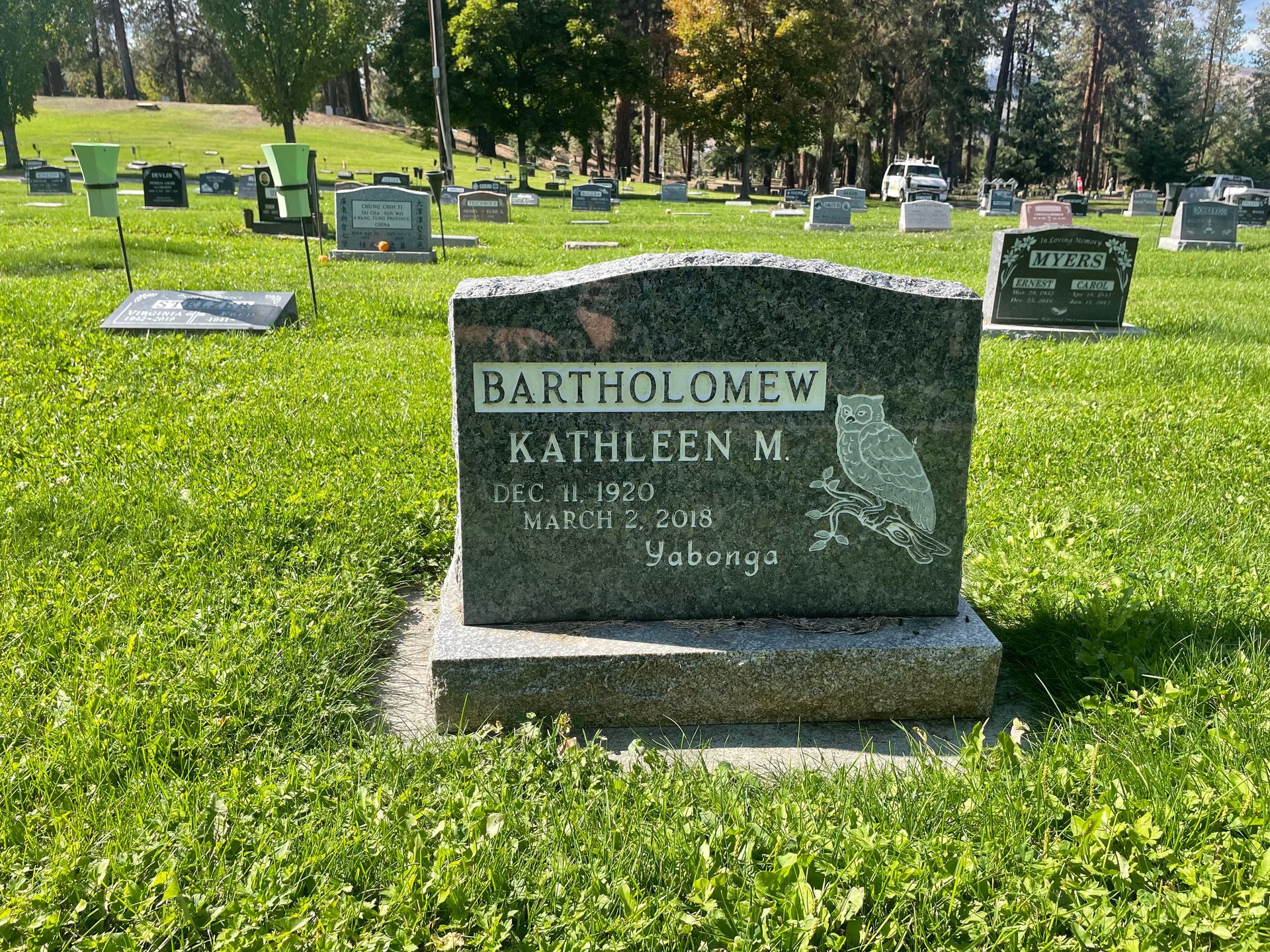 A gravestone in a cemetery with a bird on it.
