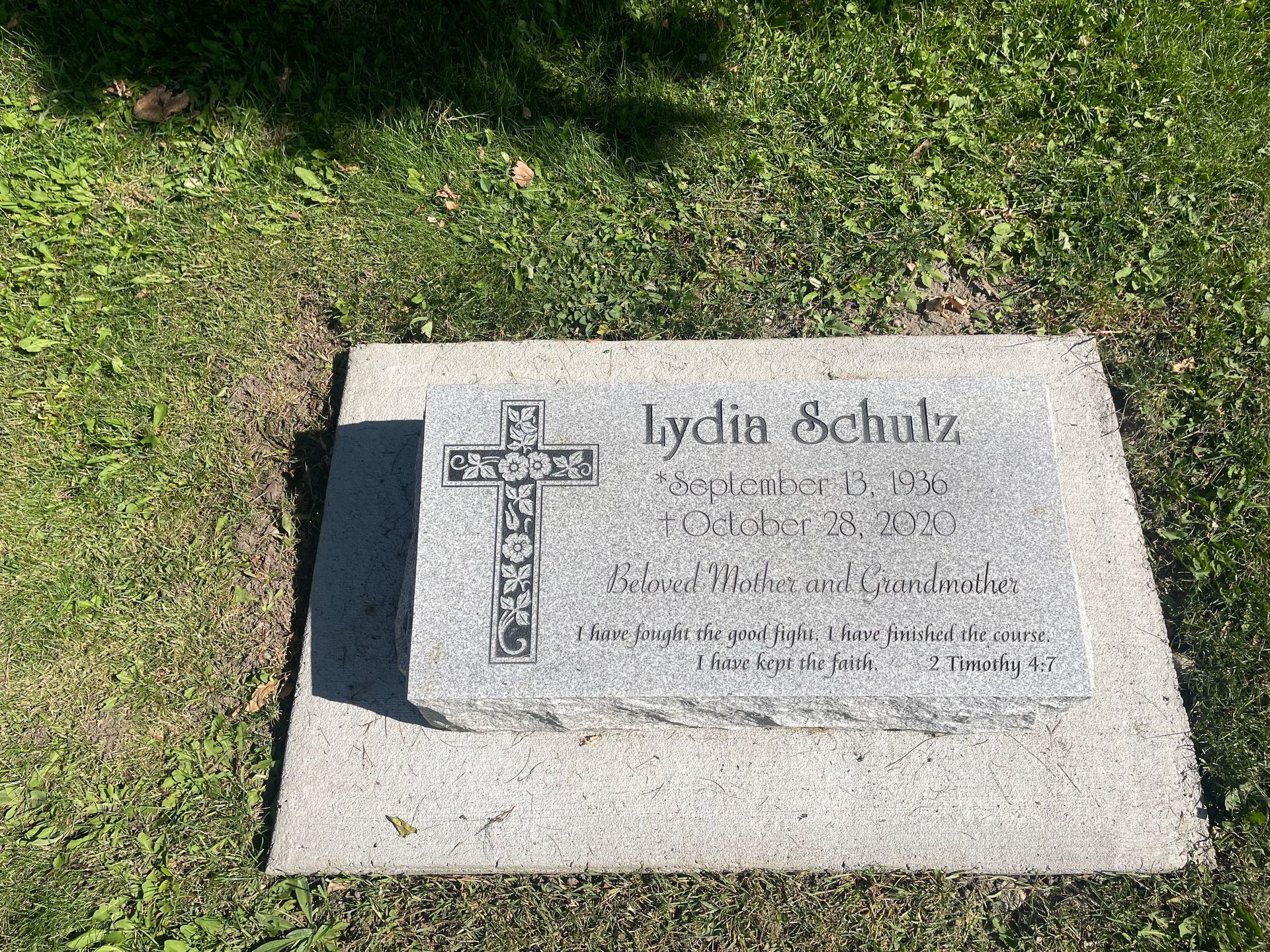 A gravestone for lydia schulz in a cemetery with a cross on it.