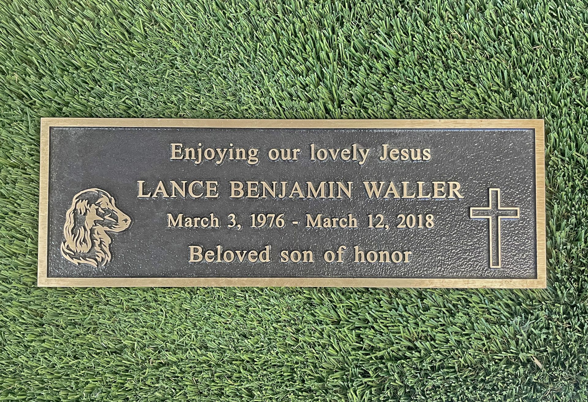 A gravestone for lance benjamin waller is sitting on top of a lush green field.