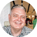 A man wearing sunglasses and a plaid shirt is smiling in a circle.