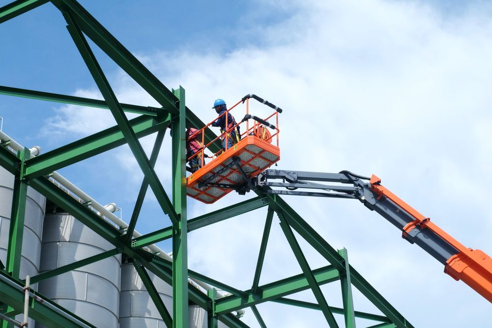 Workers in an Orange Lift Inspecting a Green Steel Structure Against a Cloudy Sky — Lifters Hire in Cambridge, TAS