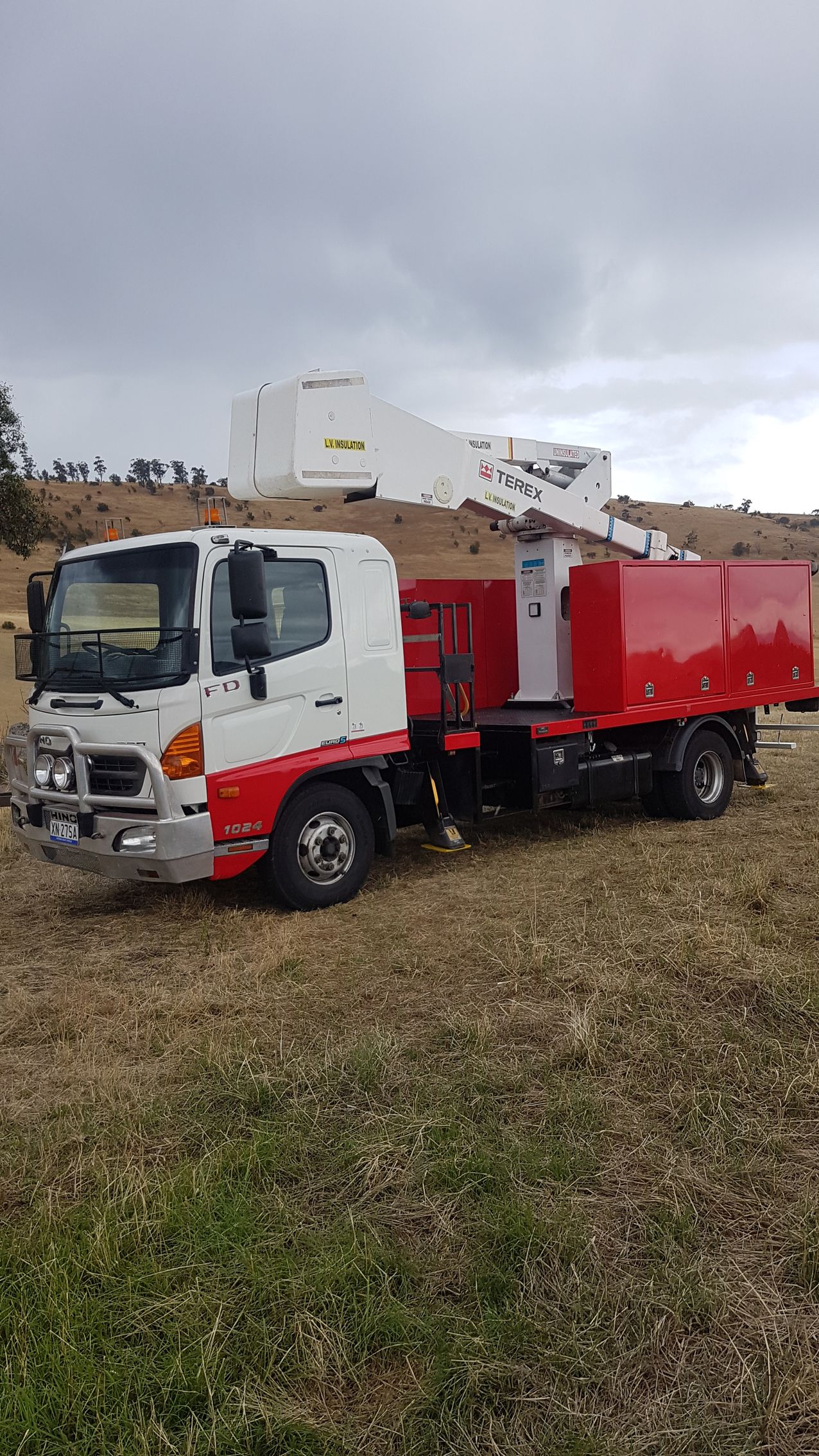 White and Red Utility Truck With a Crane Parked in a Grassy Field — Lifters Hire in Cambridge, TAS