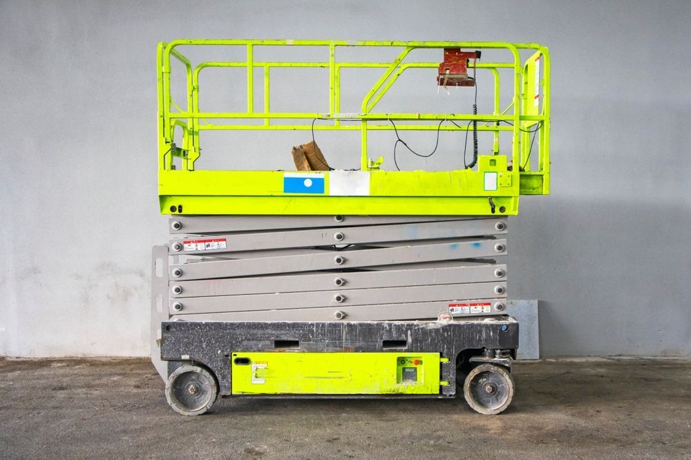 Yellow Scissor Lift Platform With Extended Railings, Parked Indoors Against a Gray Wall — Lifters Hire in Cambridge, TAS