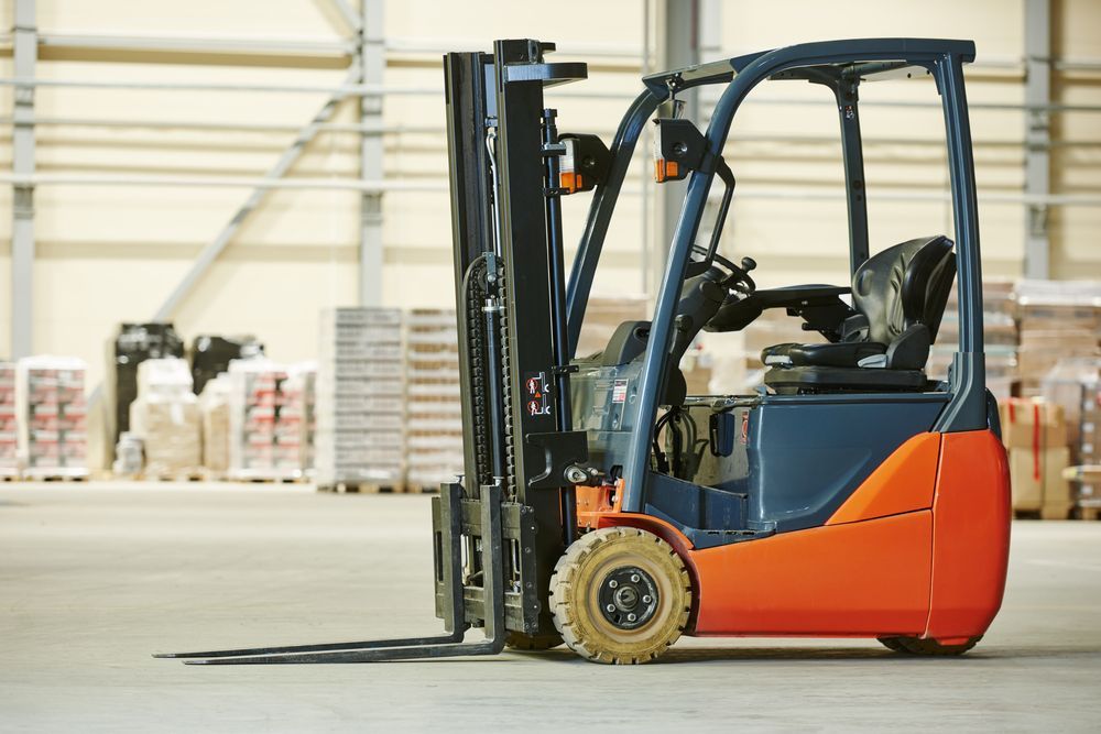 Orange and Blue Forklift Parked in a Warehouse Aisle With Stacked Pallets in the Background — Lifters Hire in Cambridge, TAS