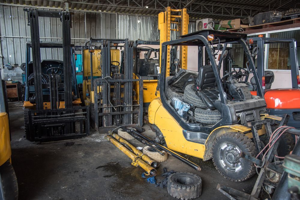 Warehouse With Several Forklifts, Including a Yellow ONE, Parked in a Dim Industrial Garage — Lifters Hire in Cambridge, TAS