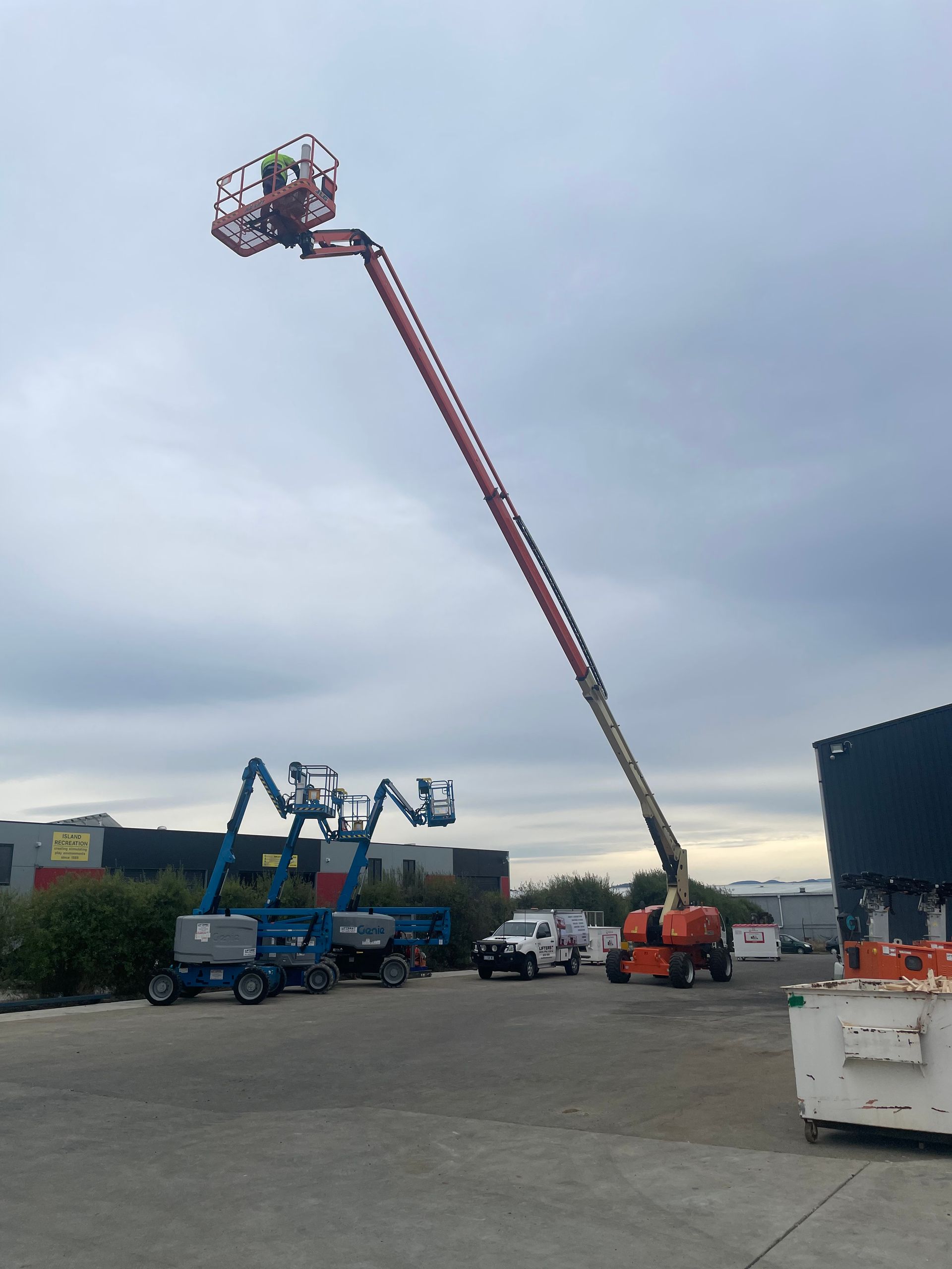 Cherry Picker Lift Raised High Over a Parking Lot With Trucks and Equipment — Lifters Hire in Cambridge, TAS