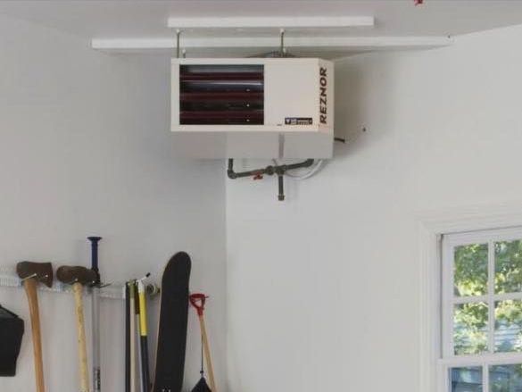 A reznor heater hangs from the ceiling of a garage