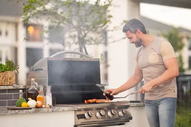 A man is cooking food on a grill in a kitchen.
