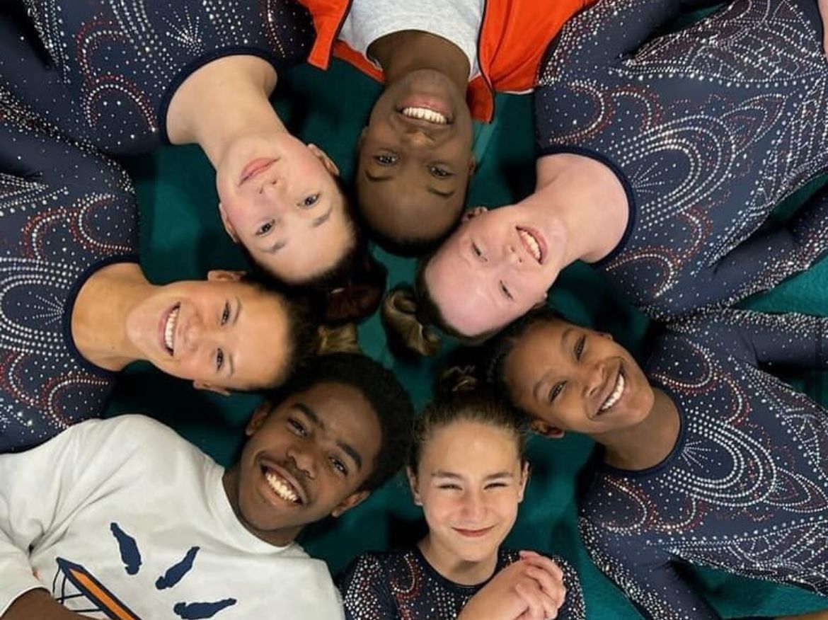 A group of people are laying in a circle and smiling
