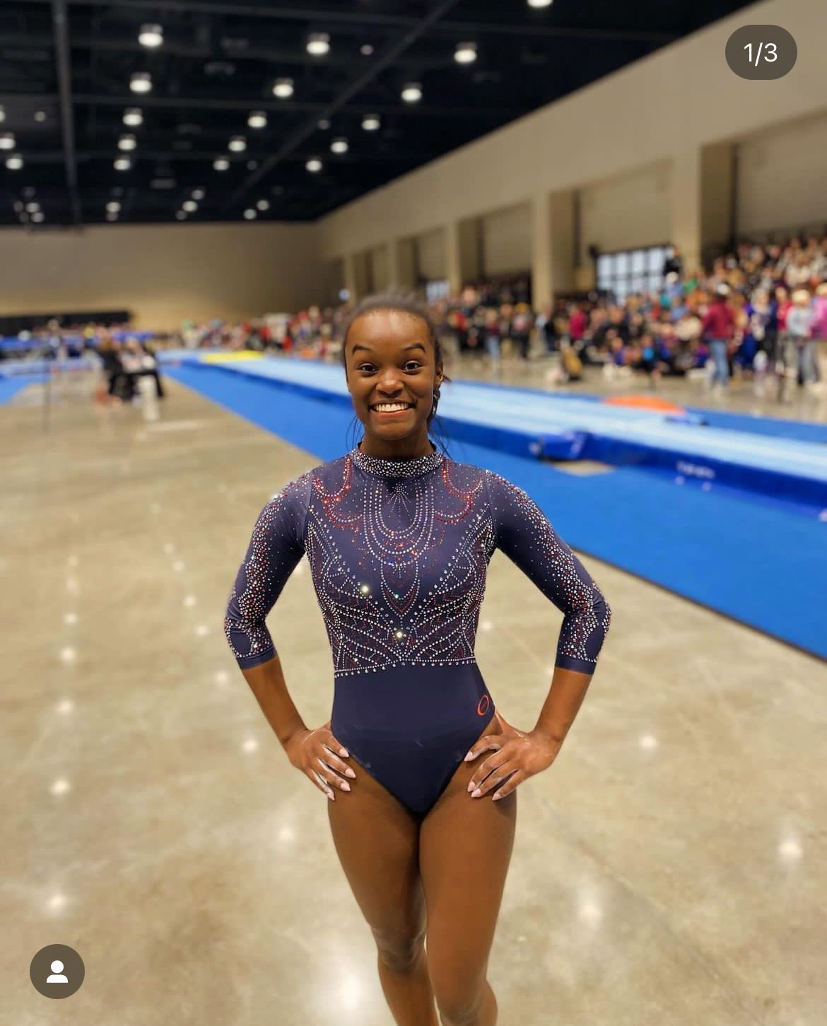 A woman in a leotard is standing in a gym with her hands on her hips