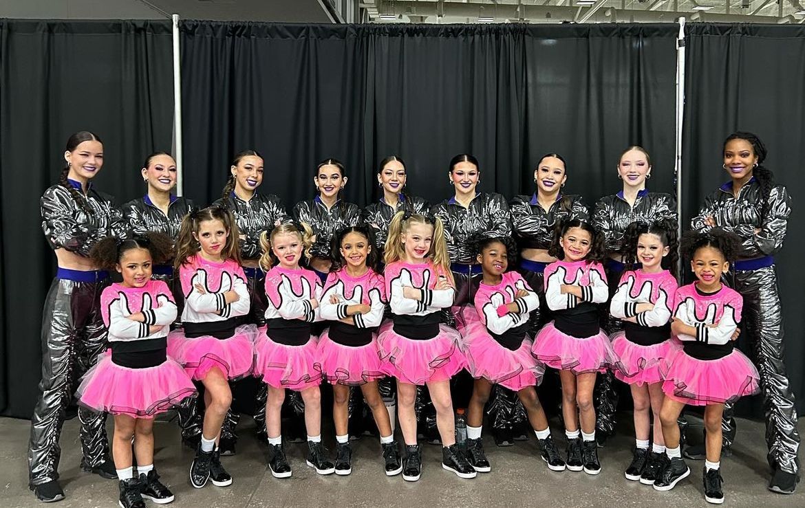 A group of young girls in pink tutus are posing for a picture.