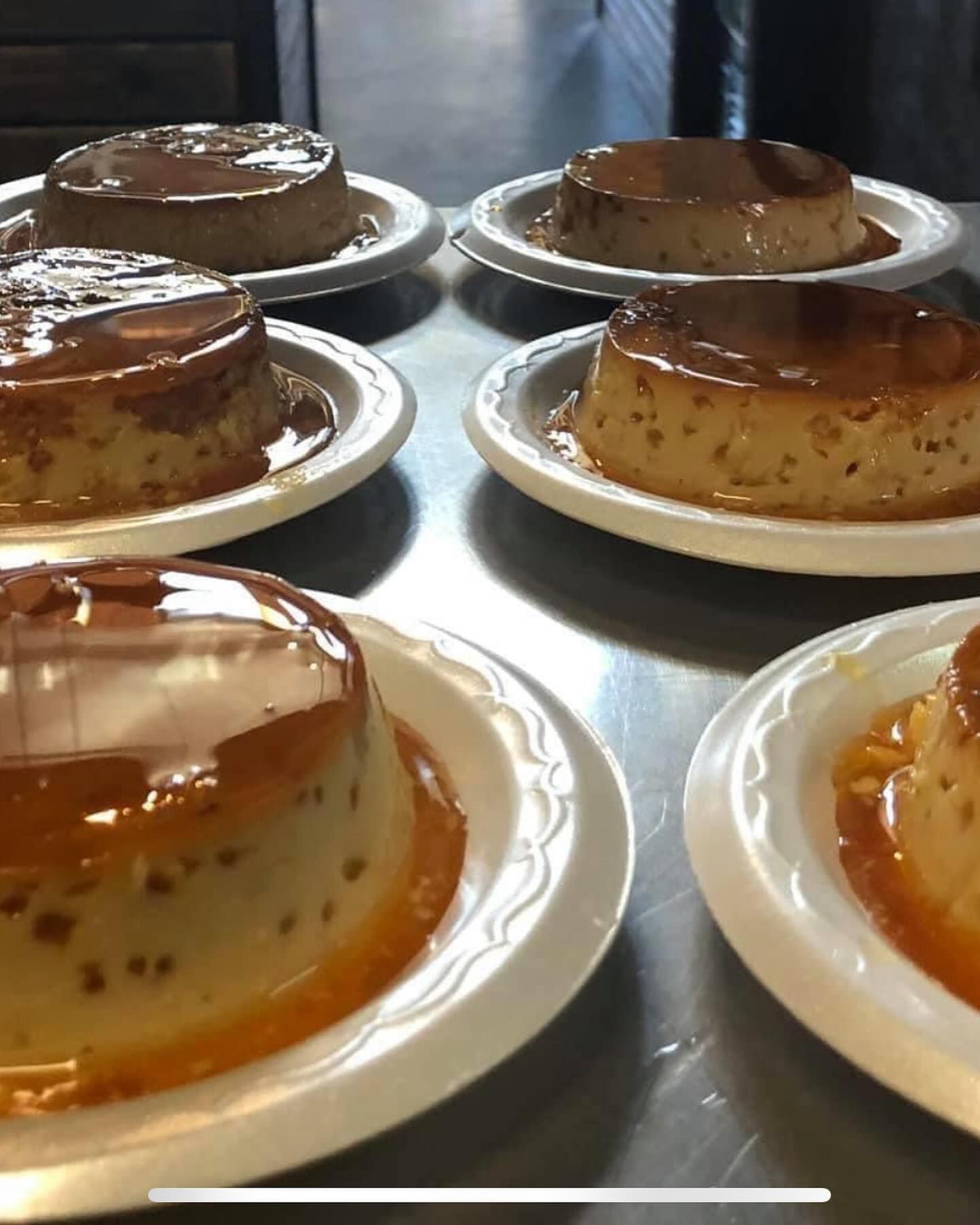 A bunch of flan desserts on plates on a table