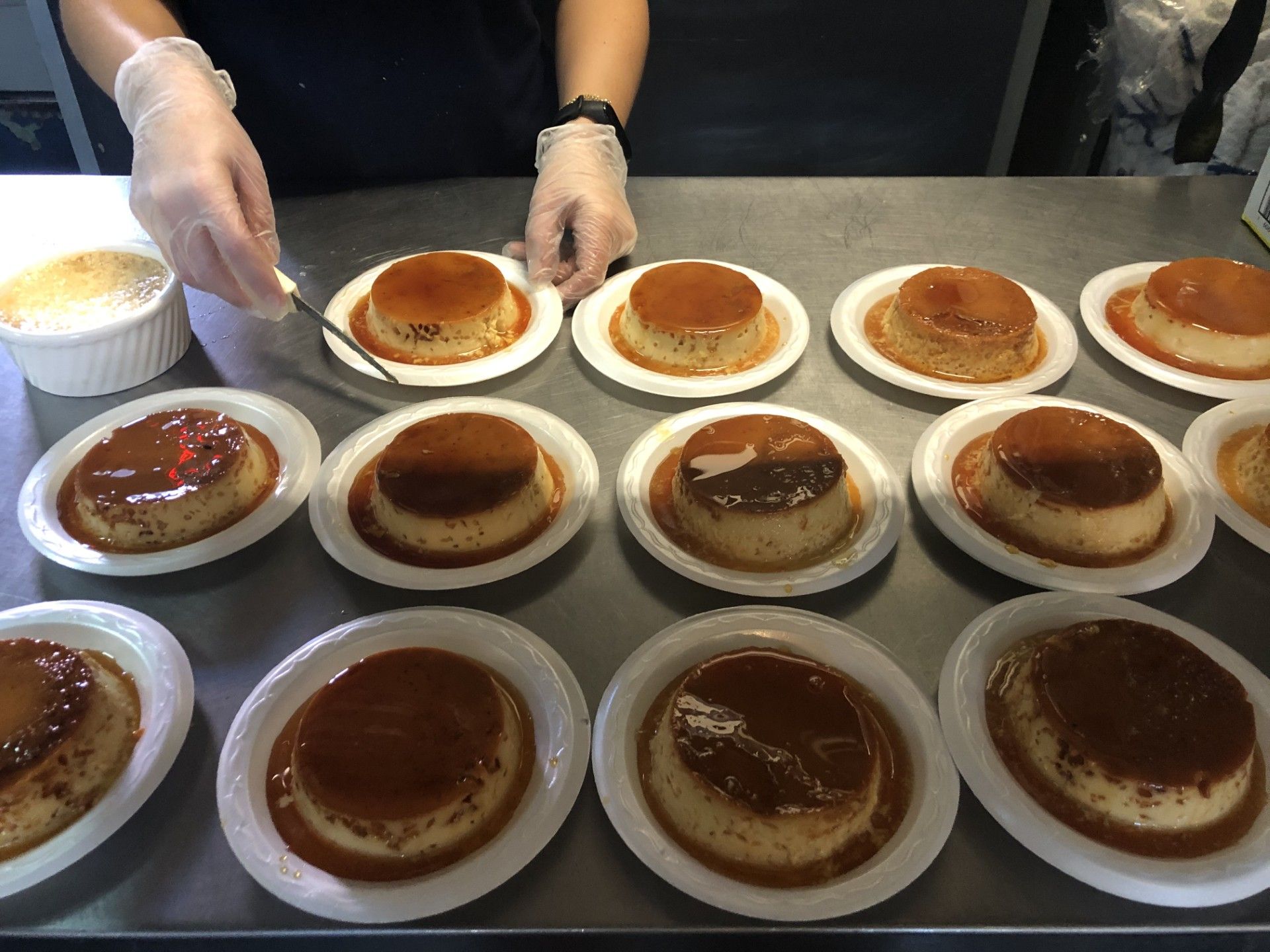 A person is preparing desserts on plates on a table.