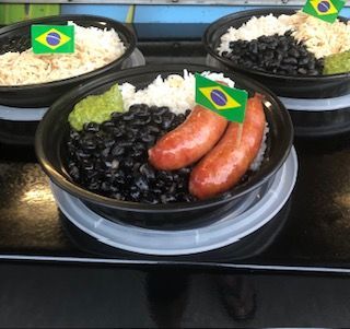 Three bowls of food with beans rice and sausage with flags on them