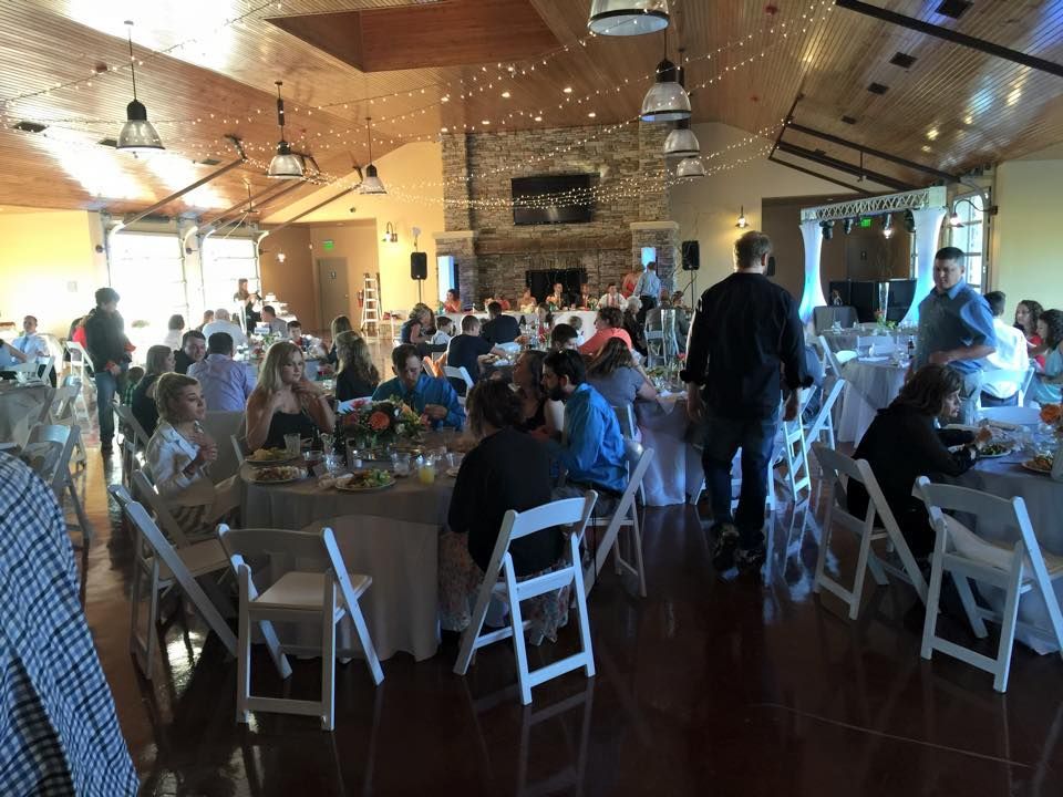 A large room filled with people sitting at tables and chairs at a wedding reception.