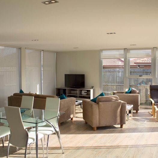 Spacious living room with tan furniture, dining table, TV, and sunny windows.