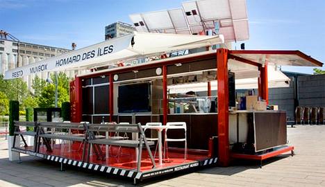 Red and black food stand, with solar panels, outdoor seating. 