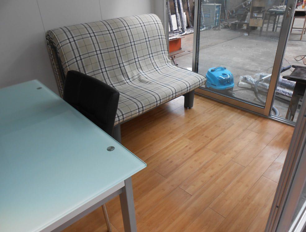 A small seating area with a patterned sofa, a table, and a view of an industrial space.