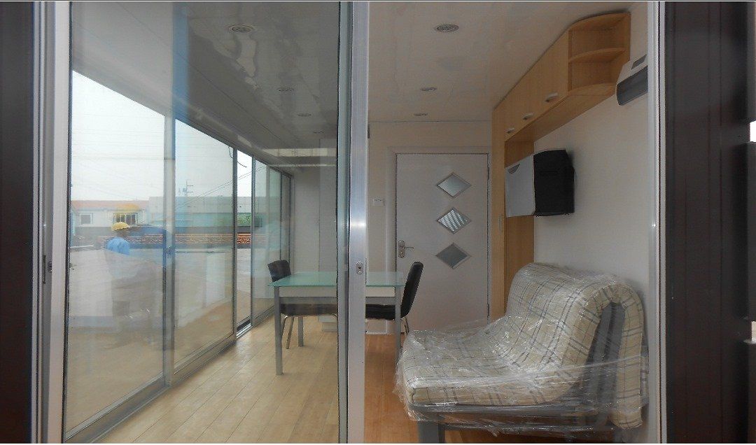 Interior view of a room with sliding glass doors, a table, chair, and a wrapped armchair.