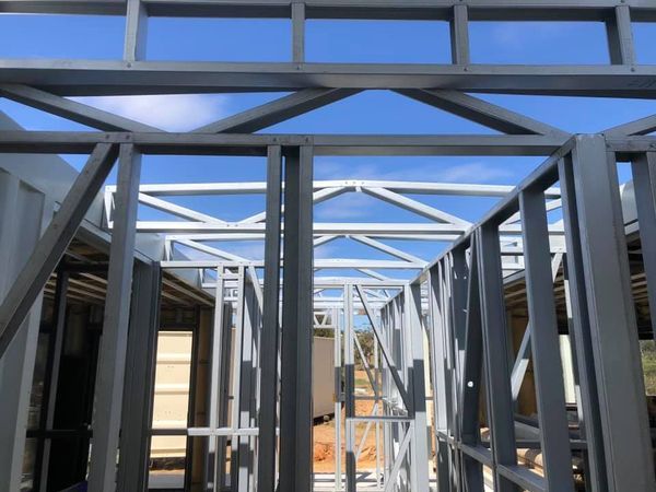 Metal framing of a building under construction, against a blue sky.