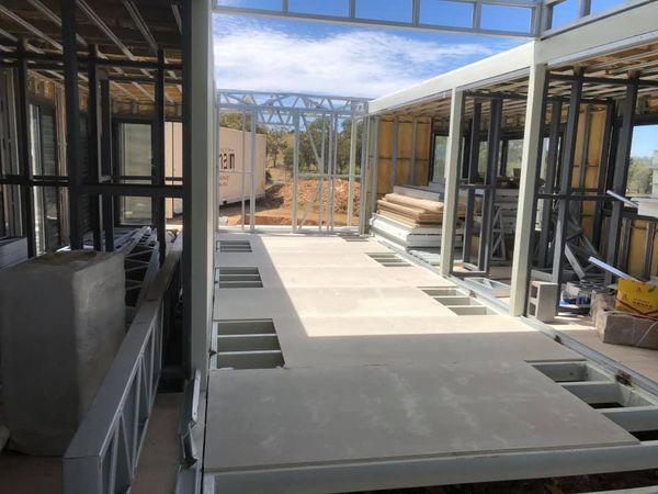 Construction site: Metal frame of a building, floorboards in place, with visible interior and exterior areas.