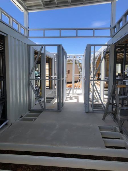 Interior view of a building under construction, featuring metal framing, concrete floor, and an open layout.