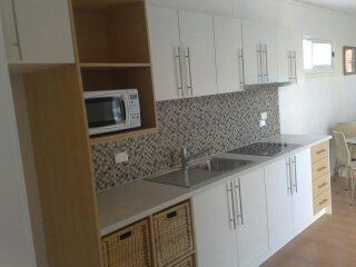 White kitchen with cabinetry, microwave, and mosaic backsplash.