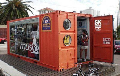 Orange shipping container converted into a store, showcasing Musto products, with a person standing inside.