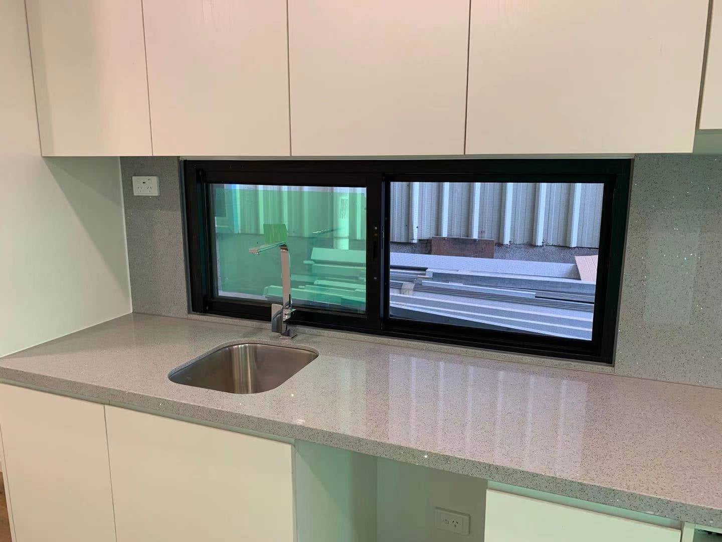 Kitchen with a sink, white cabinets, and a window overlooking an outdoor area.