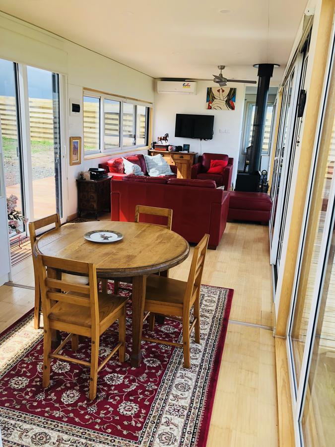 Cozy living area with red sofa, wood table & chairs, and rug. Large windows provide natural light.
