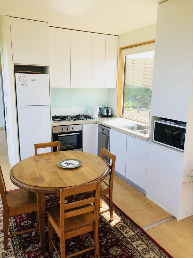 Kitchen with white cabinets, round wooden table, and a small area rug.