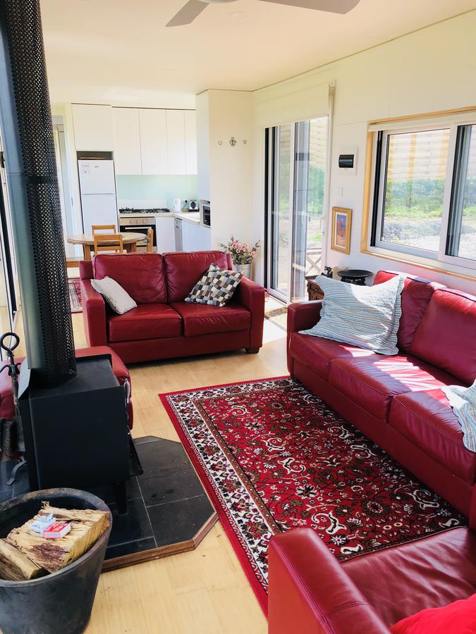 Living room with red couches, red rug, fireplace, and kitchen visible in the background.