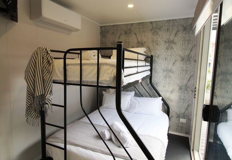 Bunk beds in a room with white bedding and a patterned wall, a towel hangs on the ladder.